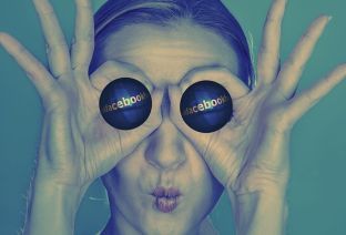 Une femme a placé une boule sur chacun de ses yeux, sur lesquelles on peut lire Facebook.