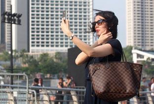 Une femme portant des lunettes de soleil réalise un selfie.