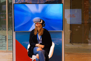 Femme assise avec un casque de réalité virtuelle sur les yeux.